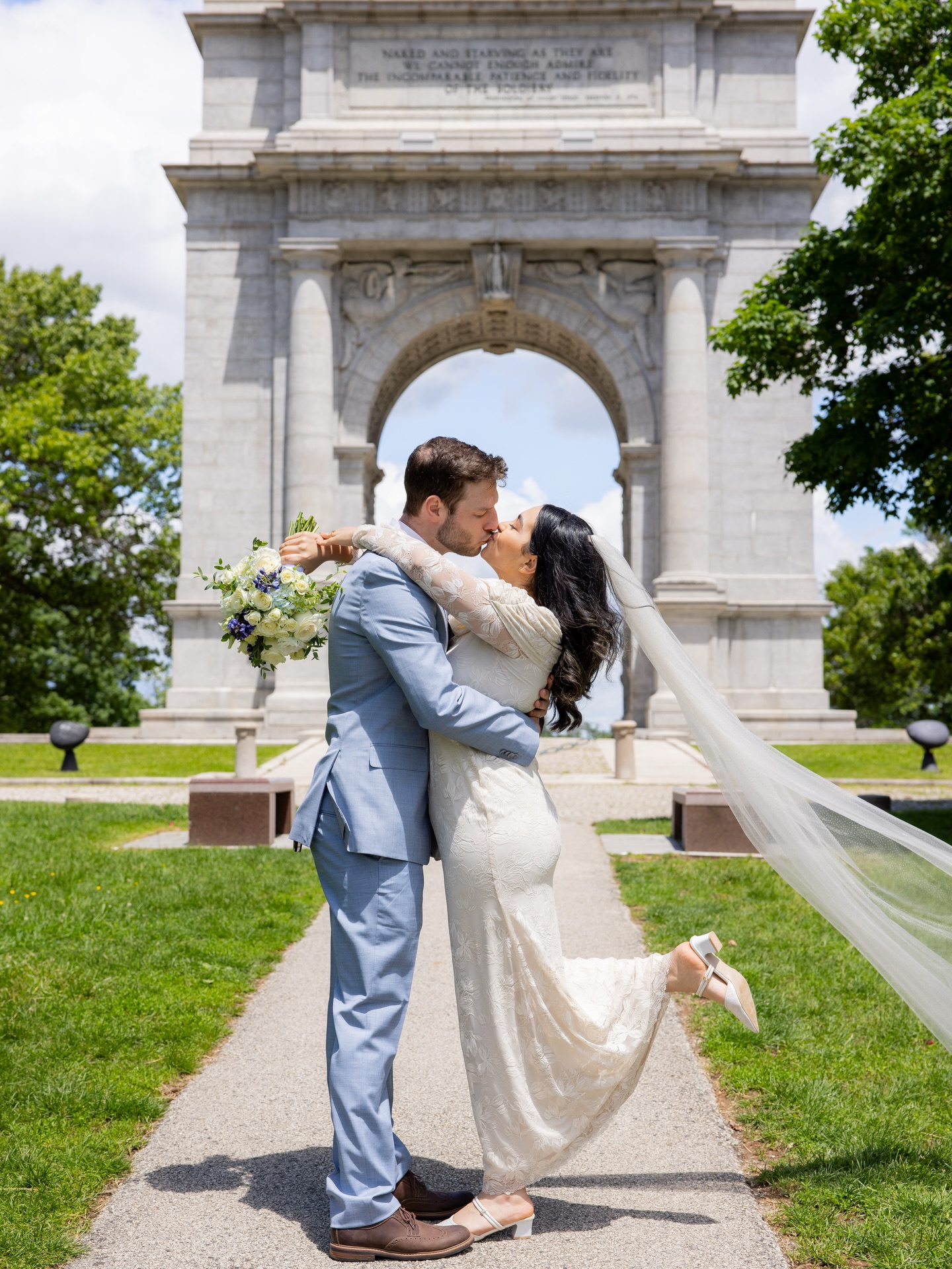 Couple kissing in front of the memorial arch, veil in the wind