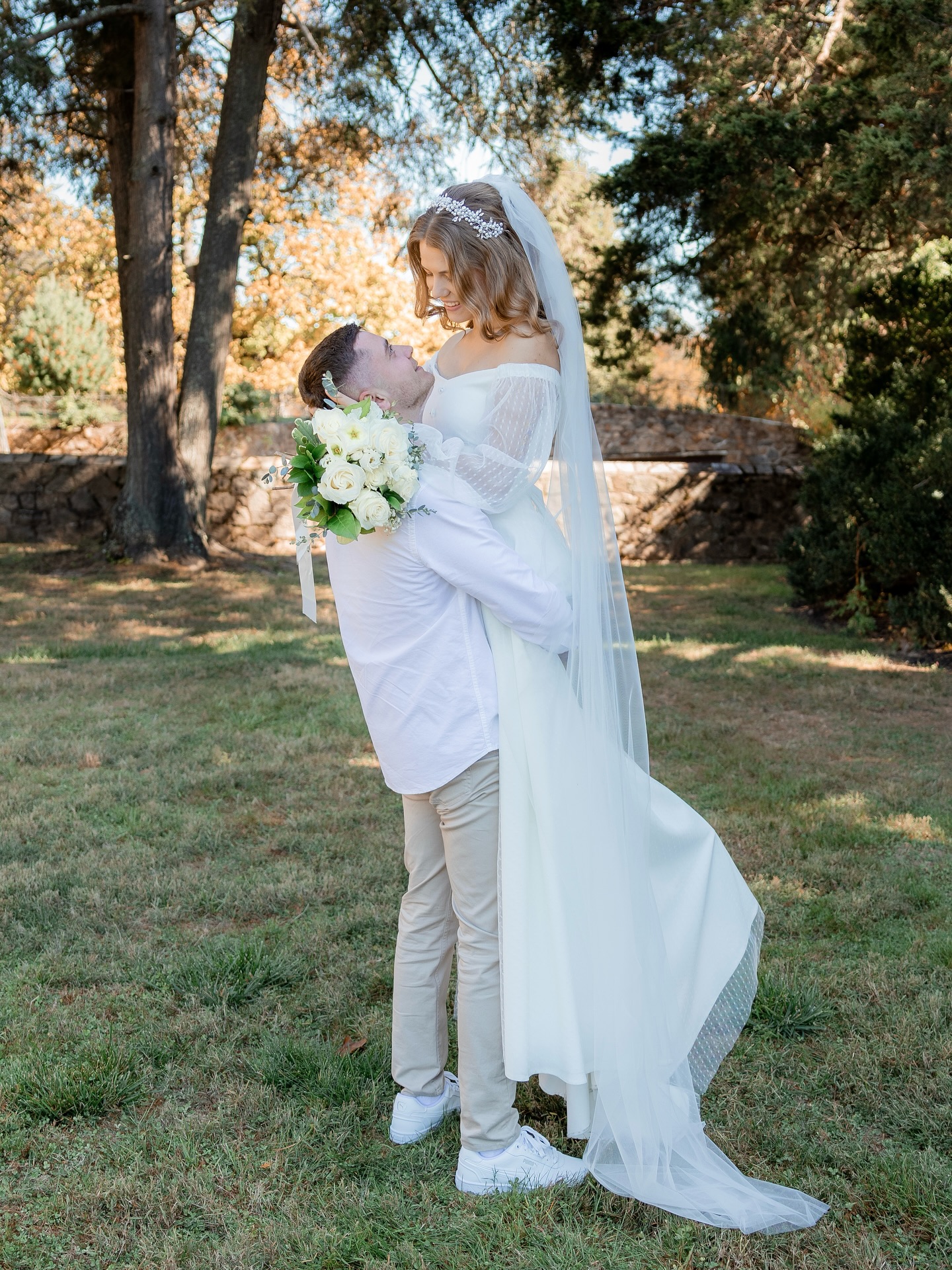 Groom lifting the bride in a sunlit park