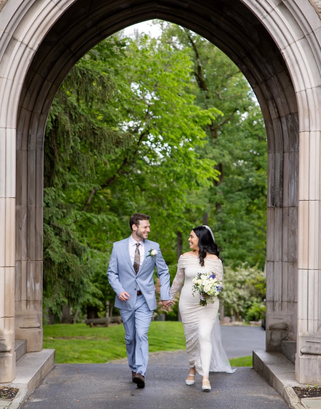 Newlyweds walking hand in hand through a gothic archway