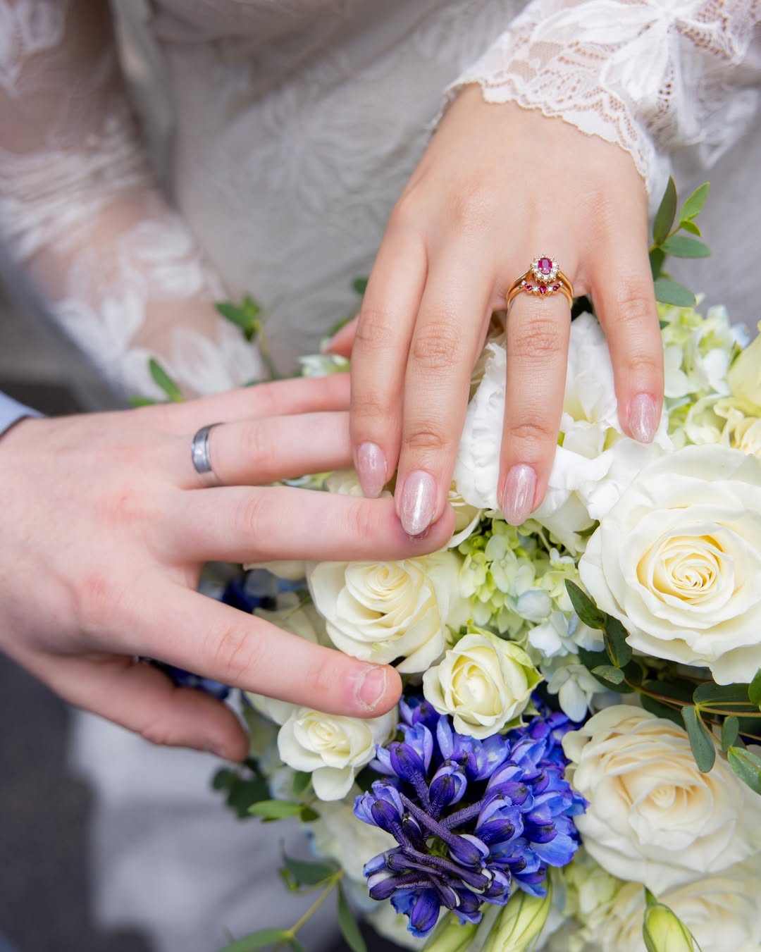 Bride and groom showing their wedding rings over the bouquet